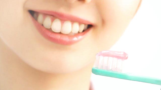 歯ブラシに塗られた歯磨き粉と女性の歯