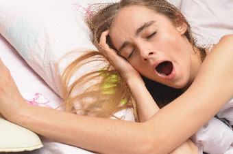 ベッドで横になったままの寝起きの女性